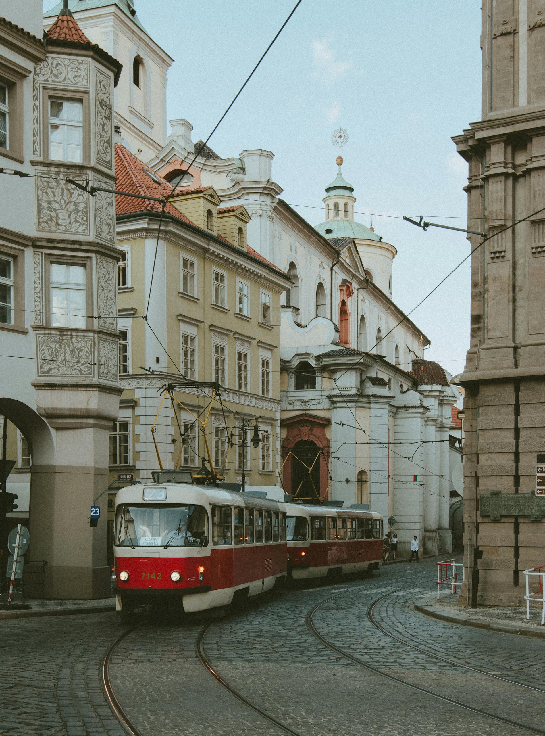 Red Tram Passing Between Concrete Buildings