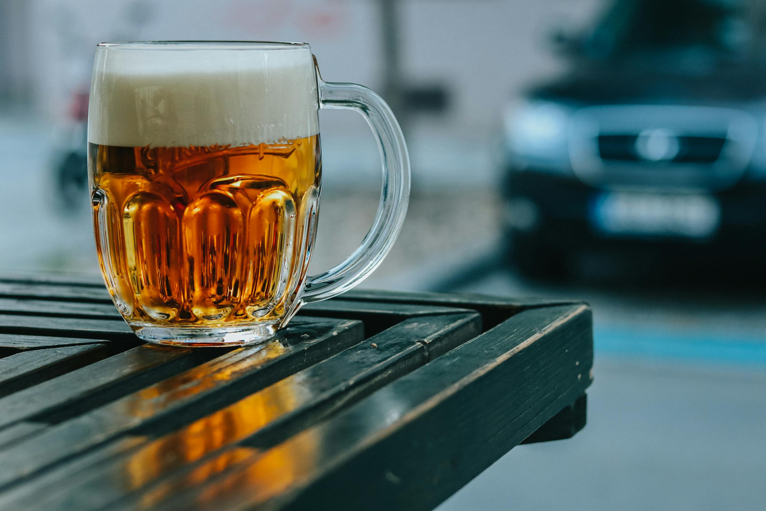 A frosty glass of pilsner beer on a wooden table at a beer garden in Prague, Czechia.