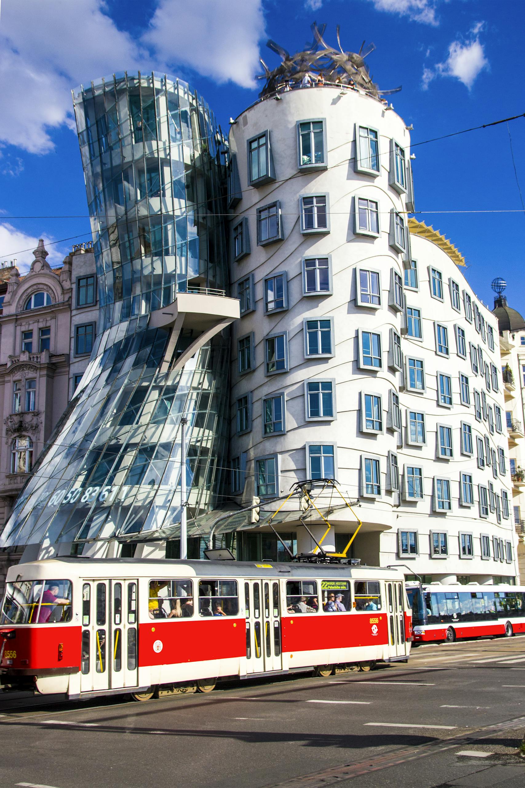 The iconic Dancing House with a tram passing by in vibrant Prague.