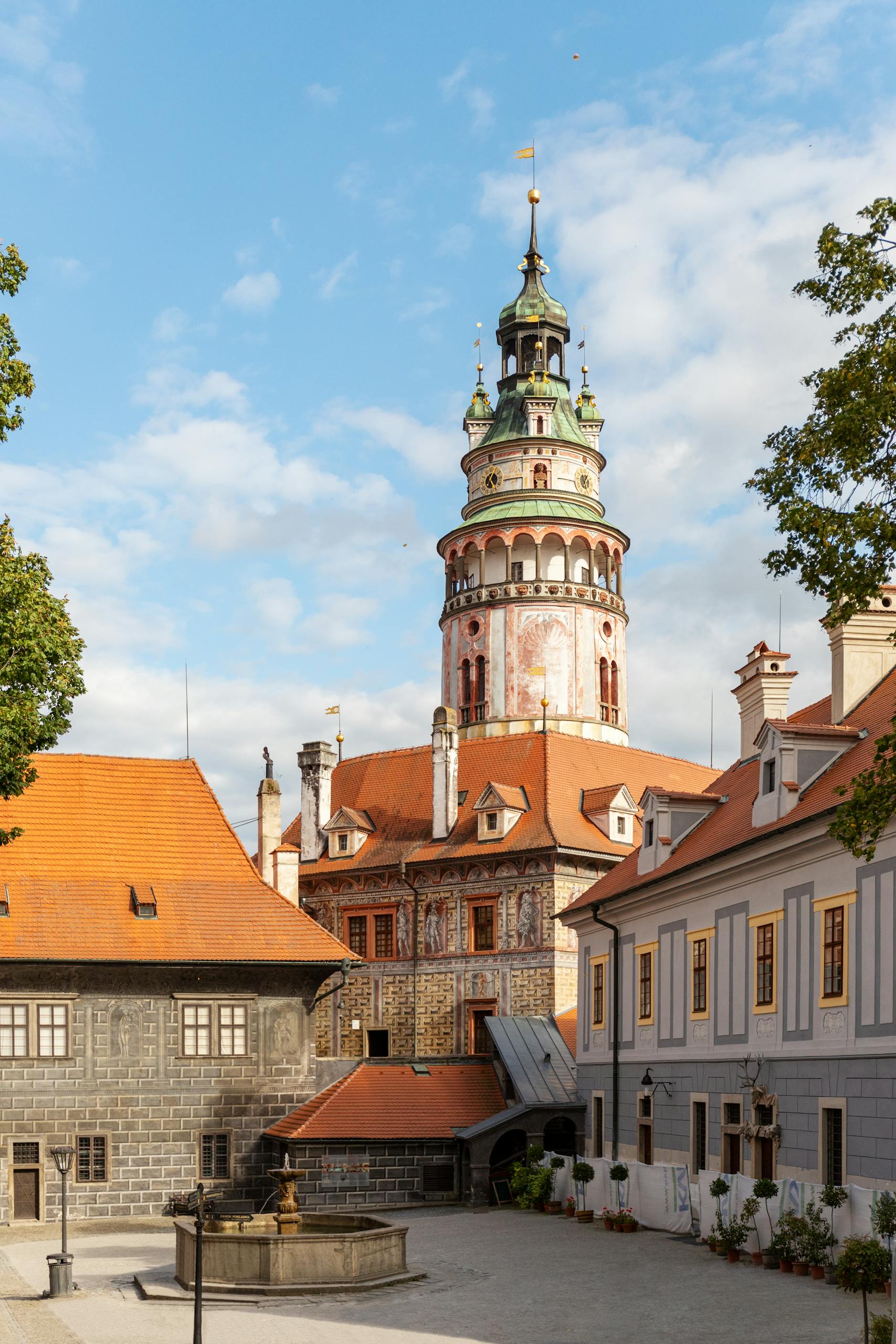 View of the Český Krumlov castle tower surrounded by historic buildings in the old town square.